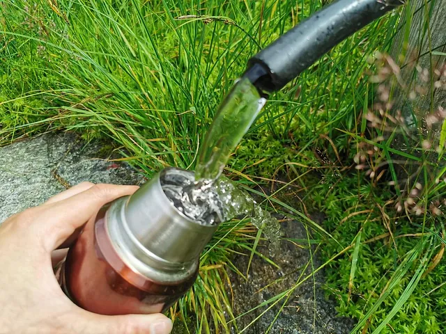 Fyller flaske med vann